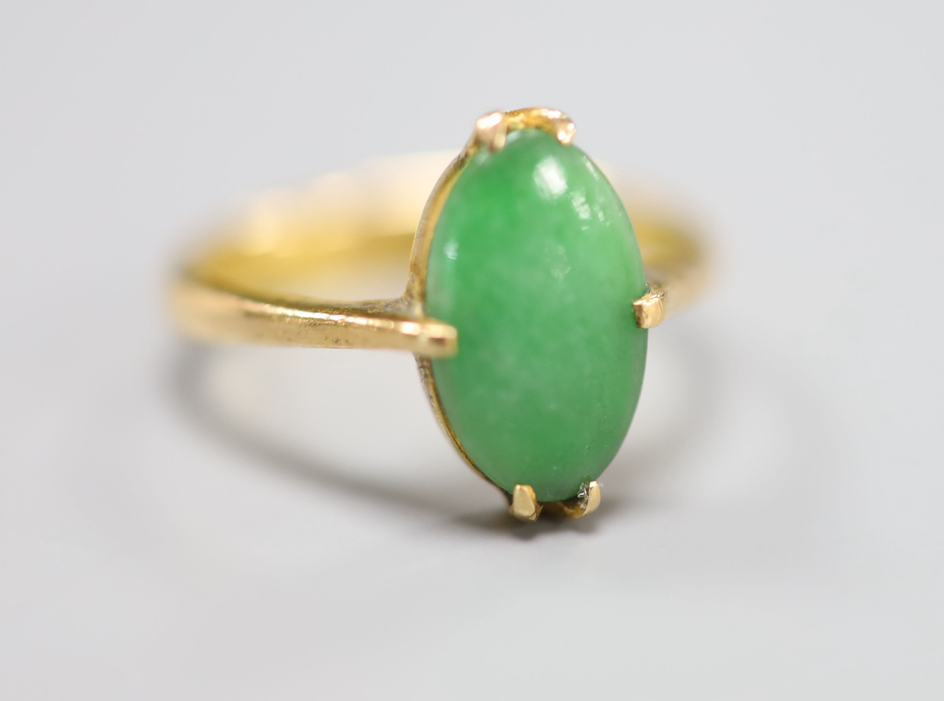 A Chinese yellow metal and oval cabochon jade set ring, size H/I, gross 3 grams.